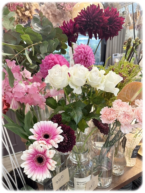 店頭に並ぶ切り花（白バラ、ガーベラ、ダリア、ピンク系の花など）