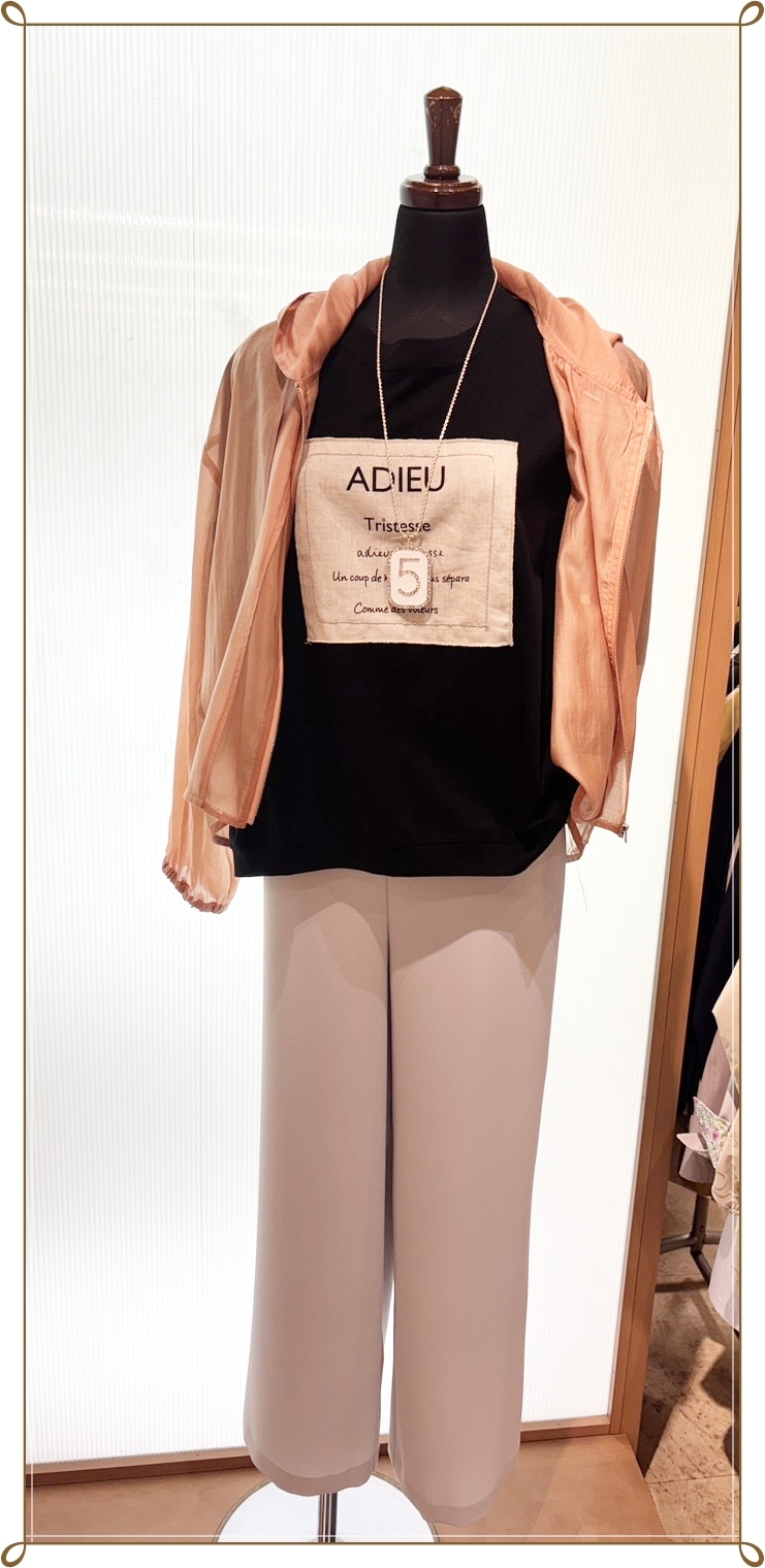 ピンクの軽い羽織りと黒のトップスを合わせた大人の春のパンツコーデ