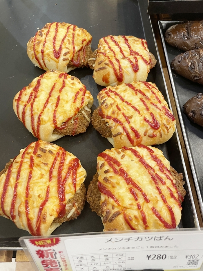 メンチカツぱん。メンチカツを包んだパンに赤いソースの線をかけた様子