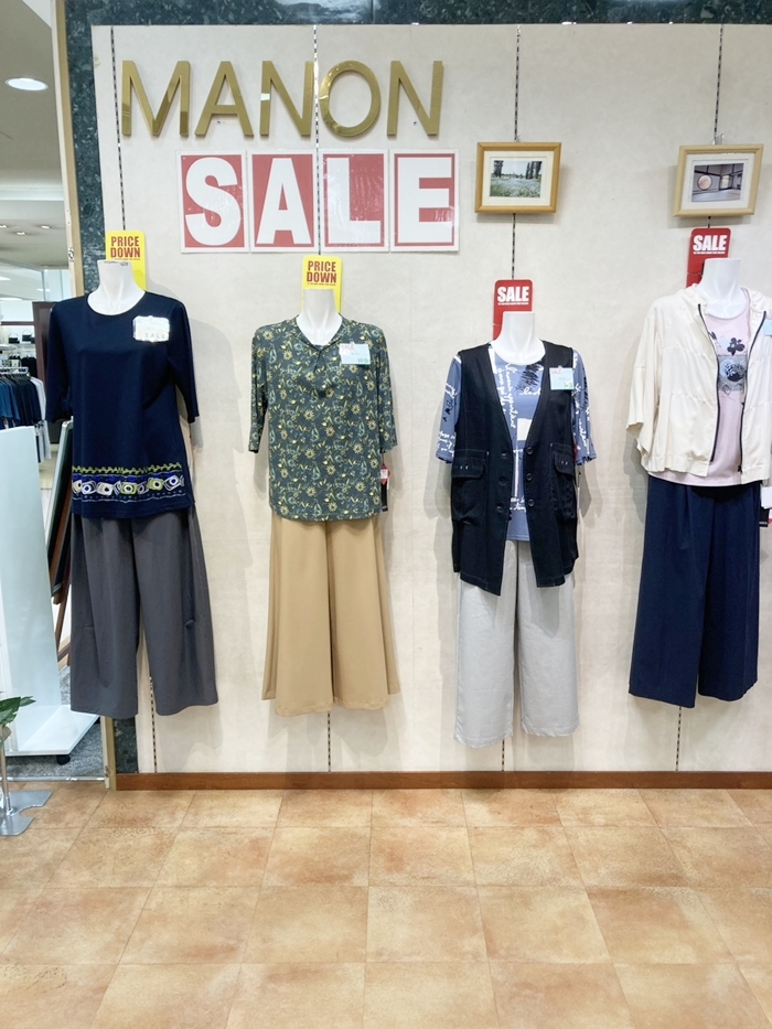 MANONフジの店頭ディスプレイ。裾に柄のある紺色トップスや花柄トップス、ベストとパンツの組み合わせ
