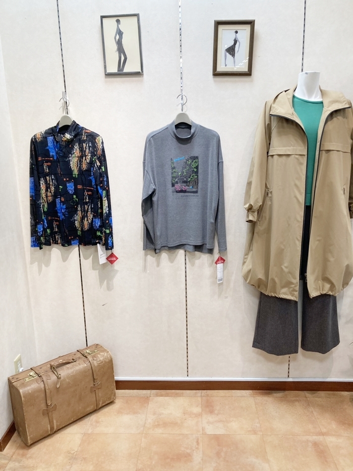 多色の柄シャツ、写真柄のグレートップス、緑色トップスにベージュのロング丈の羽織りを合わせた店頭展示